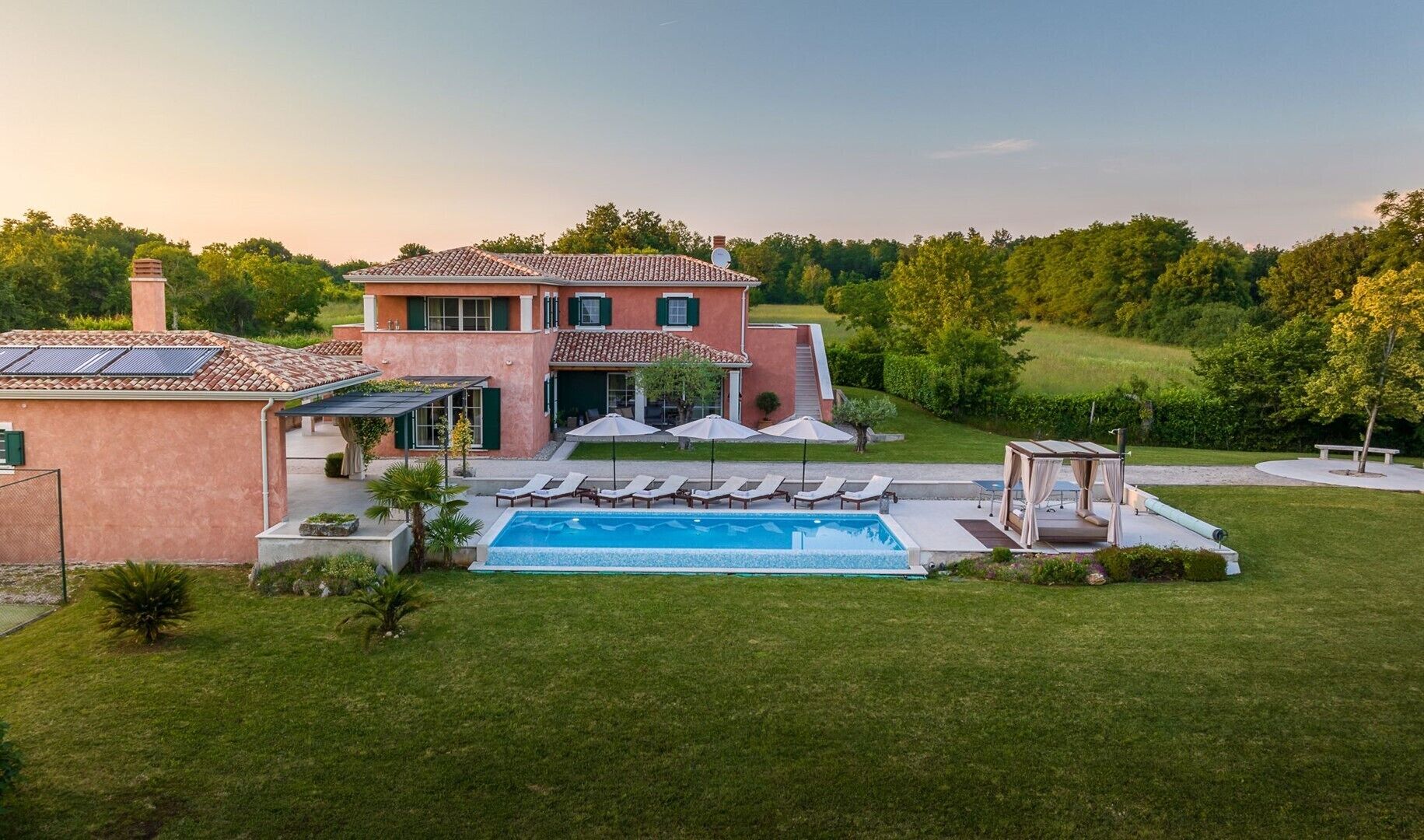 A two-story house with a swimming pool, outdoor seating, and a garden.