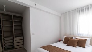 Een slaapkamer met een groot bed, een garderobe en een raam met gordijnen.