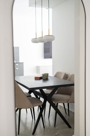 Uma zona de refeições moderna com uma mesa de madeira escura, cadeiras bege e uma luminária pendente minimalista.