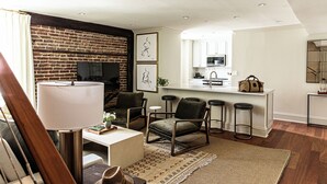 Een moderne woonkamer met een bakstenen muur, een flatscreen televisie en een eetgedeelte met barstoelen.