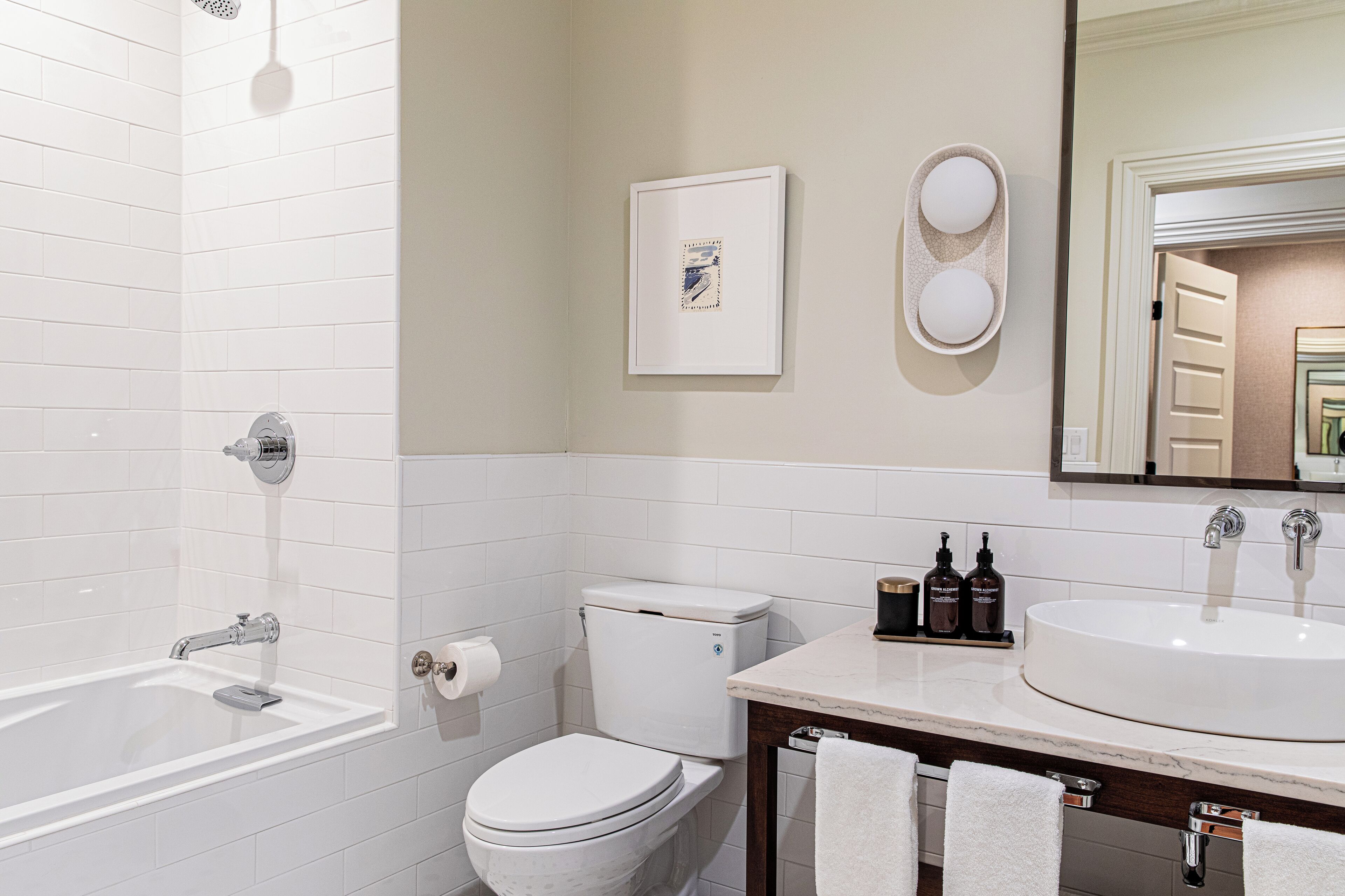 A bathroom with a bathtub, toilet, sink, and a mirror.
