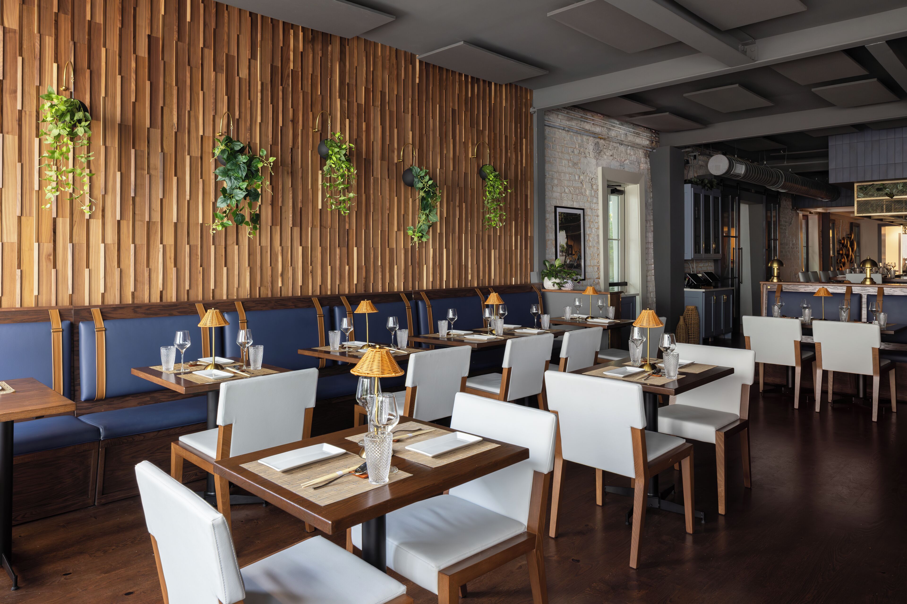 A restaurant with wooden panel walls, white chairs, and tables set for dining.