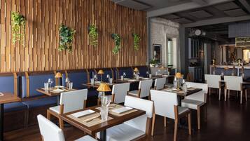 A restaurant with wooden panel walls, white chairs, and tables set for dining.