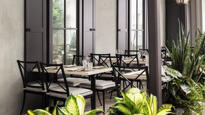 Een restaurant met een modern interieur, zwarte stoelen, witte tafels en grote ramen.