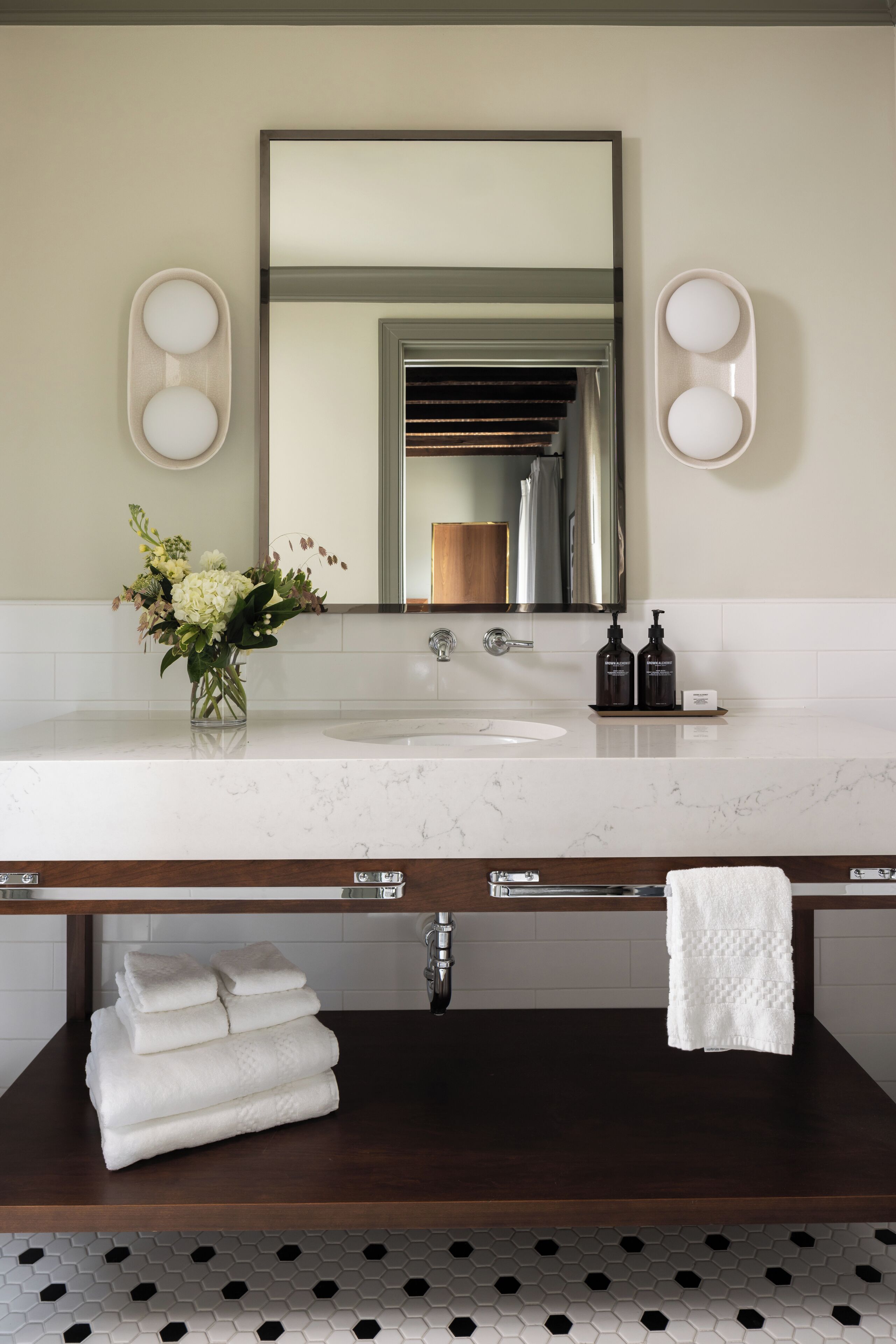 A modern bathroom with a marble sink, a large mirror, and a wooden vanity.