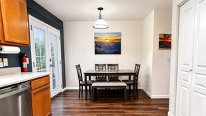 Una cocina con armarios de madera, lavavajillas de acero inoxidable y un comedor con mesa y sillas de madera.