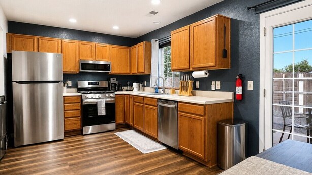 Una cocina moderna con armarios de madera, electrodomésticos de acero inoxidable y vistas a través de un ventanal.