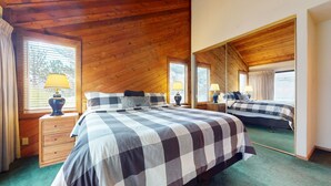 A bedroom with a checkered bedspread, wooden ceiling, two bedside tables with lamps, and a large mirror reflecting the room. - Mammoth Sierra Townhomes #23 4 Bedroom Condo by RedAwning (Mammoth Lakes)