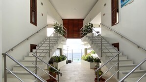 Ein modernes Interieur mit einer zentralen Treppe, die von Kübelpflanzen gesäumt wird und zu einem hellen Raum mit Aussicht führt.
