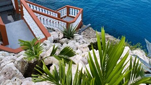 Ein Küstenblick mit einer Treppe, die zu einem Balkon mit Meerblick führt.