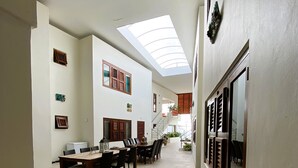 Ein geräumiger Korridor mit hoher Decke, einem Oberlicht und einem Essbereich mit langem Tisch und Stühlen.