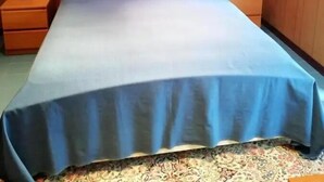 Un dormitorio con una cama grande, paredes de madera, dos cuadros enmarcados y dos mesitas de noche con lámparas.