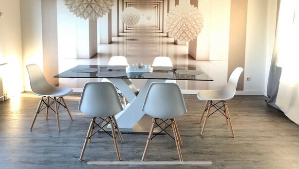 Een moderne eetruimte met een glazen tafel, grijze stoelen en een geometrisch wandontwerp.