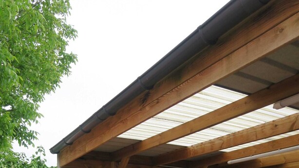A patio area with wicker furniture, a brick floor, and a wooden pergola.