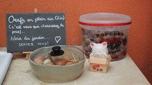 A chalkboard menu, a popcorn container, a bowl of eggs, and a small figurine on a countertop.