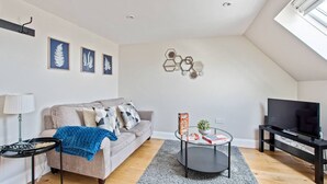 Una sala de estar moderna con sofá, mesa de centro, mueble para televisión y decoración mural.