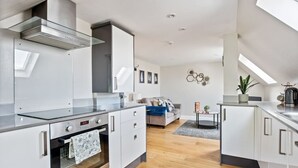 Una cocina moderna con armarios blancos, una campana de acero inoxidable y un horno empotrado.