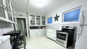 A kitchen with white cabinets, a black countertop, a stove, and a refrigerator. - American Adventure AC family beach home (Atlantic City)