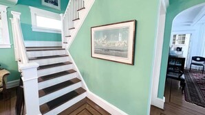 A staircase with white railings leading to a landing, a framed picture on the wall, and a view into a dining area. - American Adventure AC family beach home (Atlantic City)
