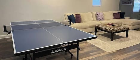 Et ping pong-bord i en stue med en sofa og et sofabord.