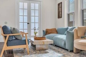 A living room with a blue sofa, a beige armchair, a wooden chair, and a coffee table. - Montgomery Walkout, Bay & Beach (Atlantic City)