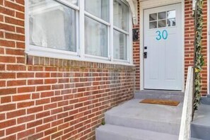 A brick building with a white door marked with the number 30, a set of steps leading to the entrance, and a small porch area. - Montgomery Walkout, Bay & Beach (Atlantic City)