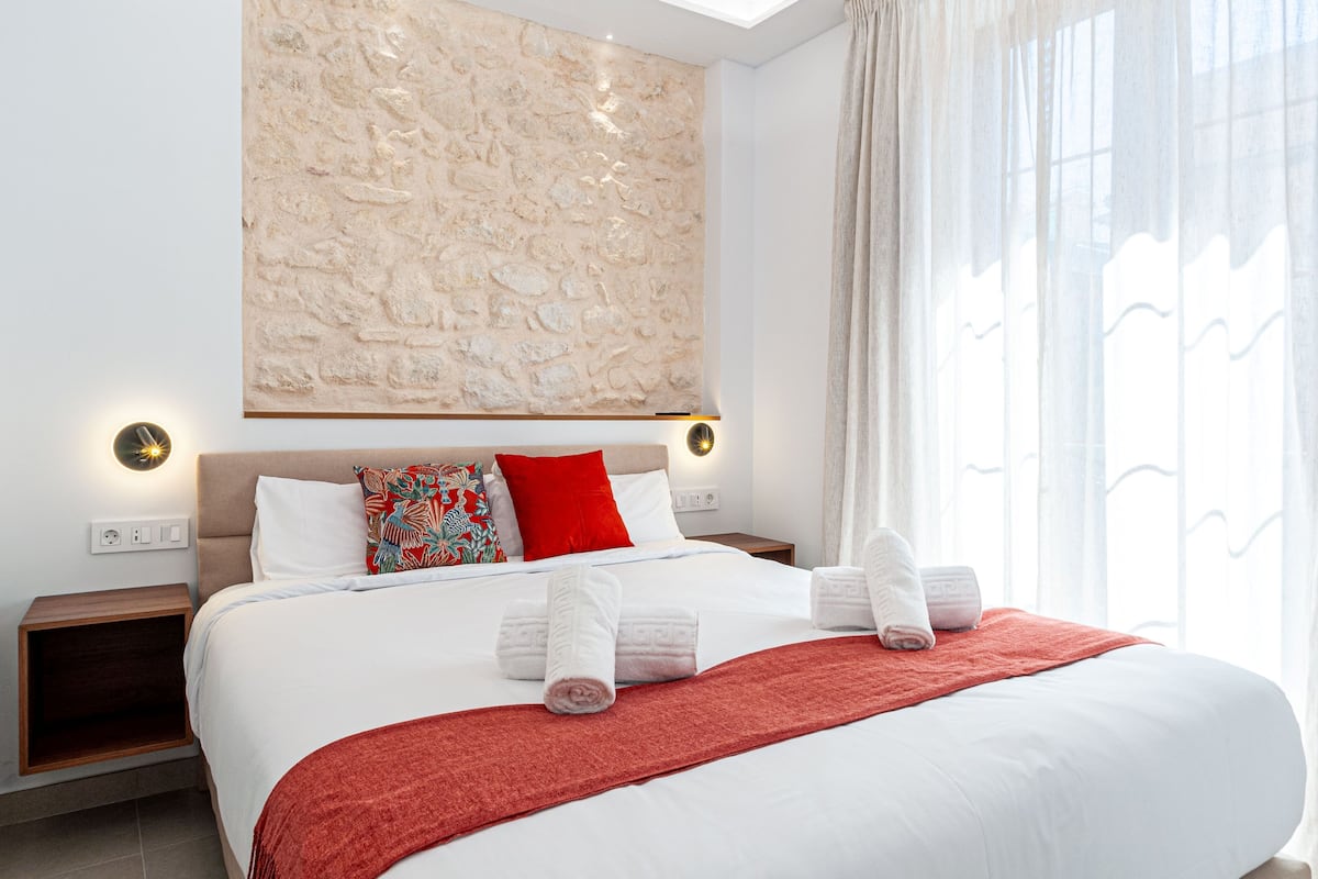 Ett modernt hotellrum med en stor säng, en vägg med dekorativa stenar och utsikt över omgivningarna.