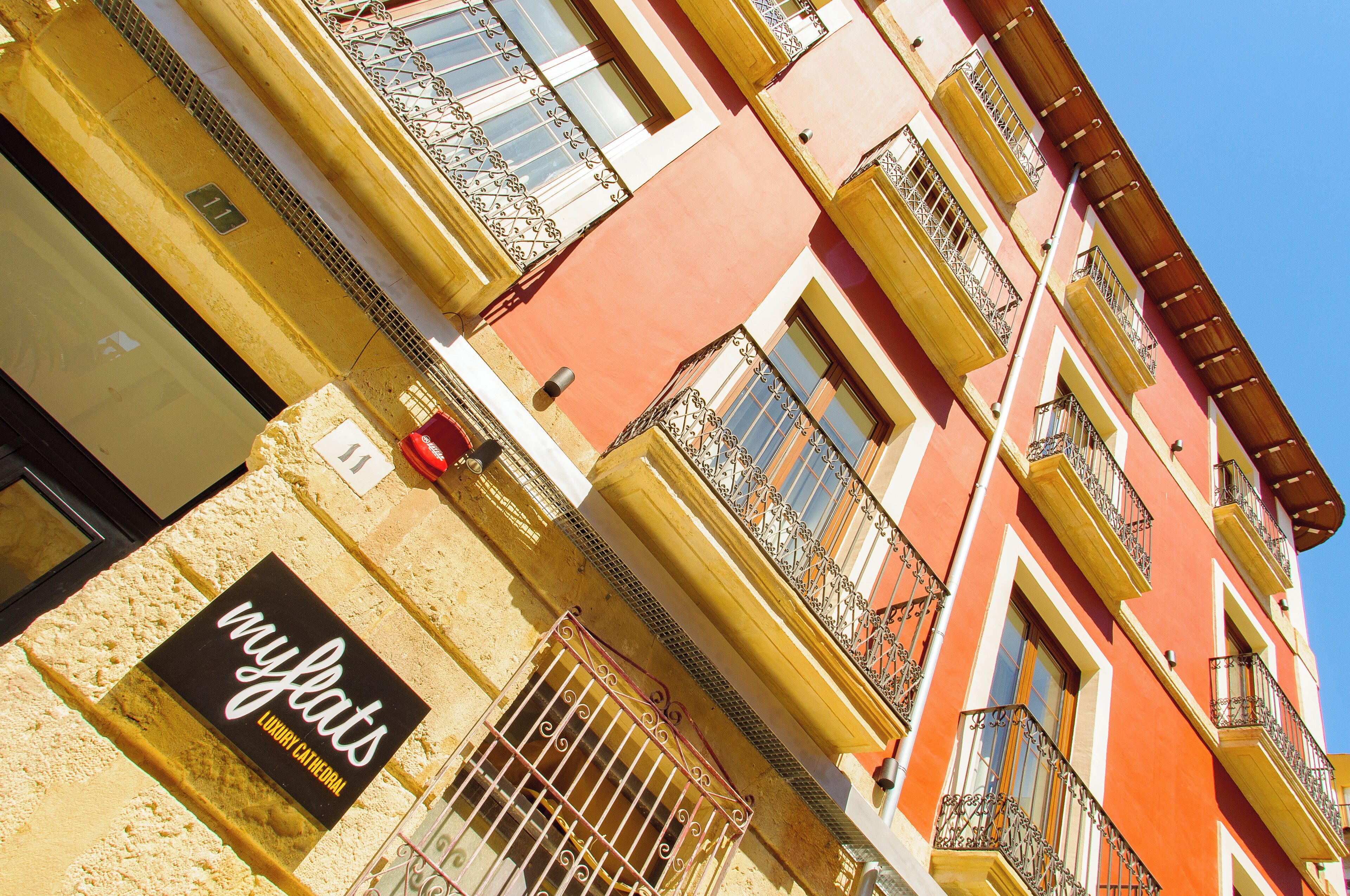 A multi-story building with balconies and a sign for 'myfats luxury cathedral'.