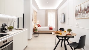 A modern, compact hotel room with a kitchenette, a dining area, and a bed with a view of the city. - Myflats Luxury Cathedral (Alicante)