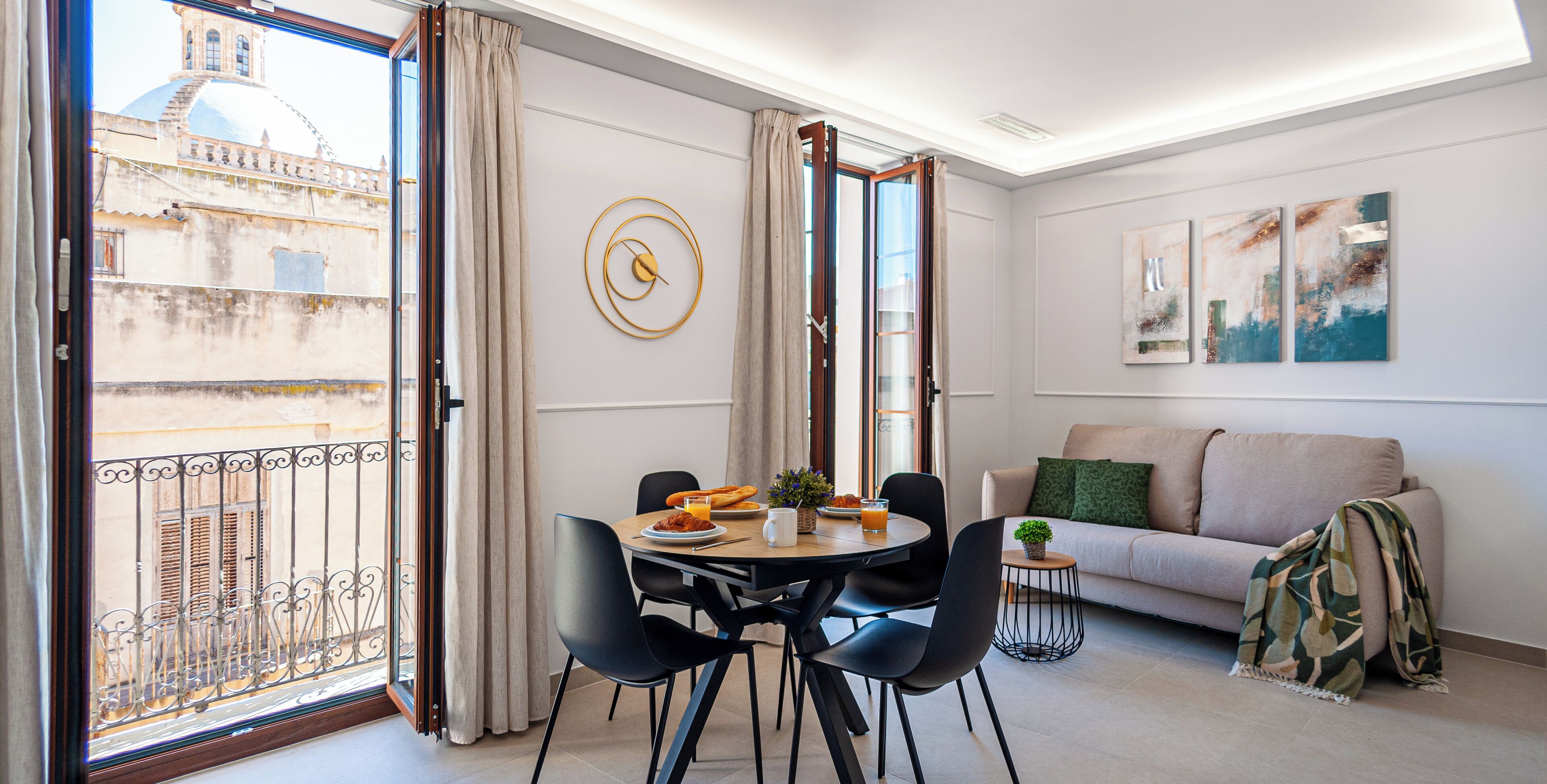 Ein modernes Wohnzimmer mit Essbereich, einer Couch und einem Balkon mit Blick auf ein Gebäude.