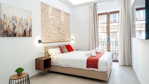 A modern bedroom with a large bed, a stone accent wall, a cityscape painting, and a balcony with a view. - Myflats Luxury Cathedral (Alicante)