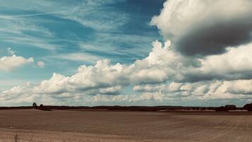 A vast open field with a clear sky and scattered clouds.