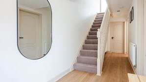 Una escalera con escalones alfombrados y una pared blanca con un espejo redondo.