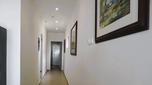 En hall med vita väggar, kakelgolv och inramade konstverk.