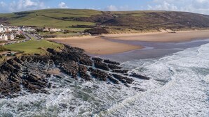 A coastal landscape with a beach, rocky shoreline, and a town with buildings.