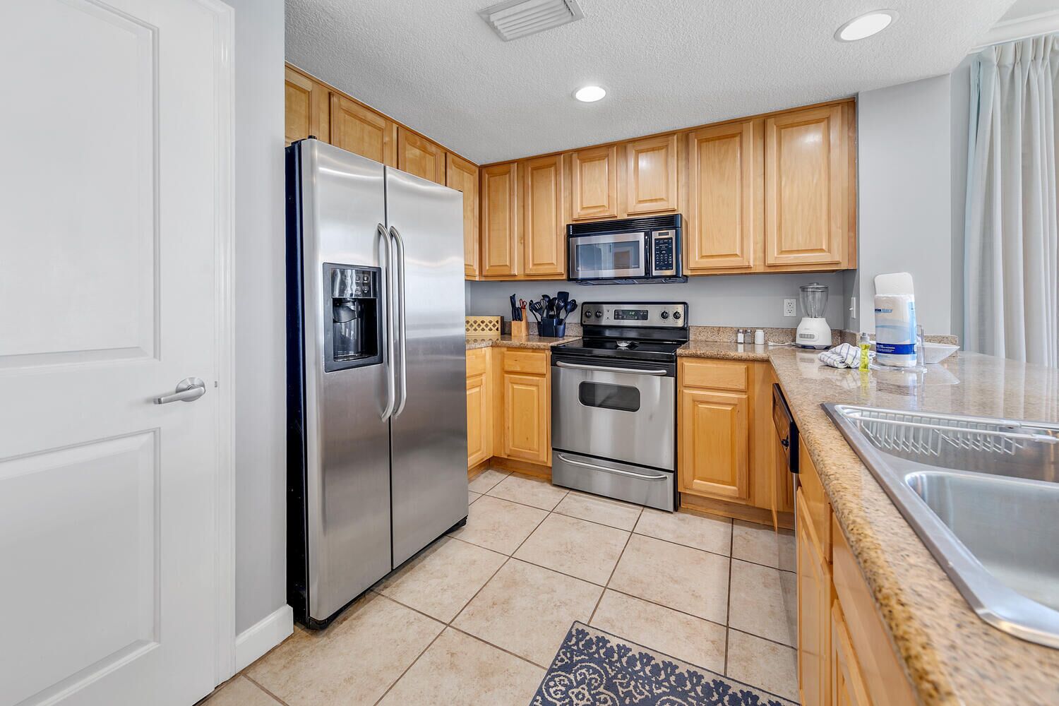 A modern kitchen with stainless steel appliances, wooden cabinets, and a granite countertop.