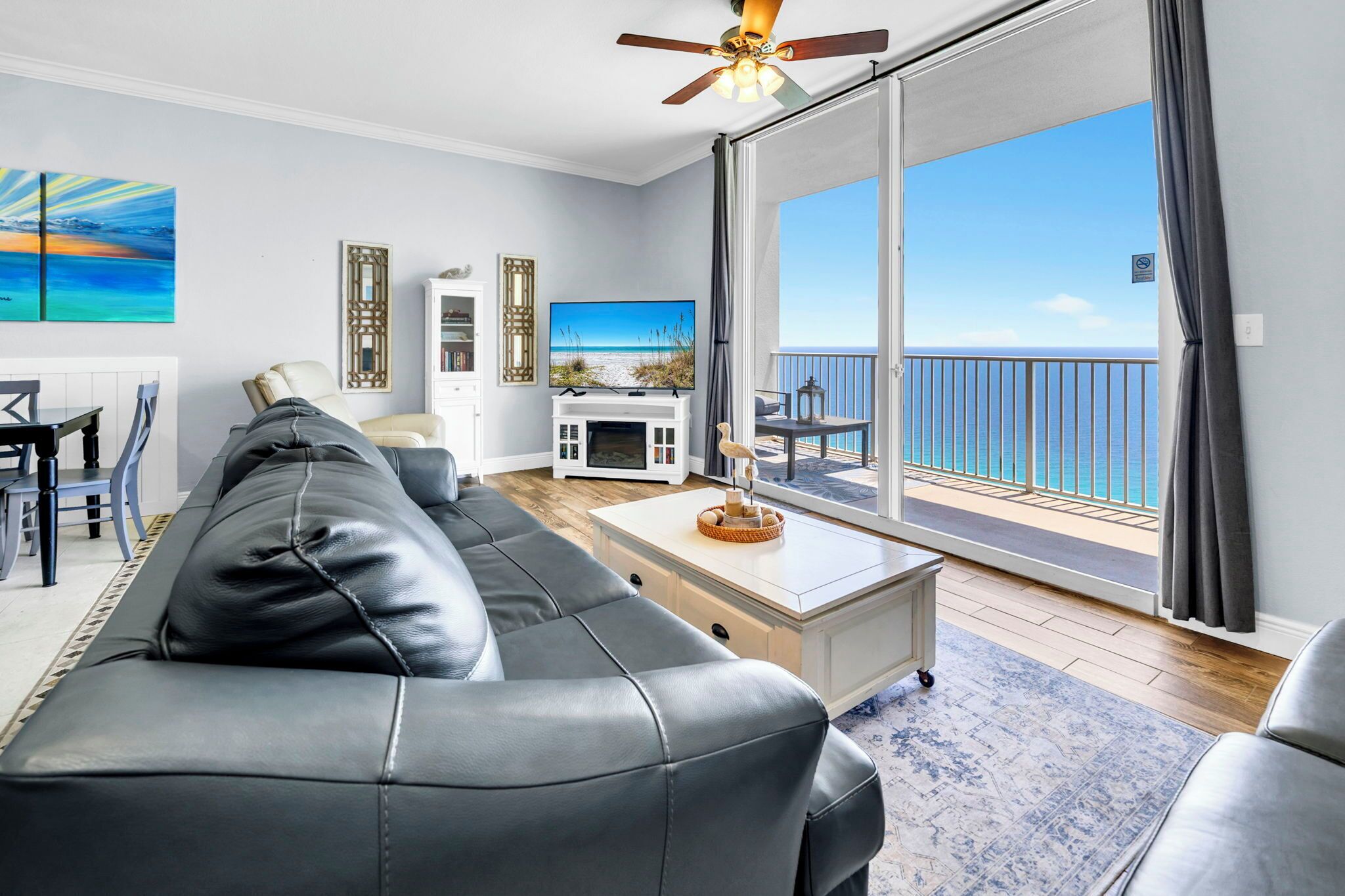 Ein modernes Wohnzimmer mit einer Ledersofa, einem Flachbildfernseher und einem Balkon mit Meerblick.