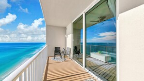 Un balcone con vista sull'oceano, un'area salotto con sedie e un parapetto in vetro.