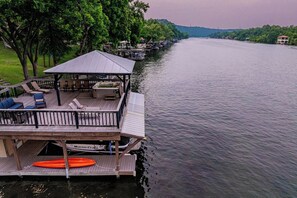 A docked boat with a covered seating area and a lifebuoy. - Lakeside Retreat | Fire Pit, Game Room & Canoe (Austin)