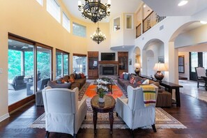 A spacious living room with a fireplace, multiple seating areas, and large windows.