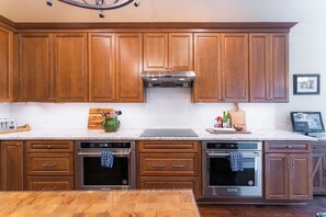 A kitchen with wooden cabinets, stainless steel appliances, and a marble countertop. - Lakeside Retreat | Fire Pit, Game Room & Canoe (Austin)