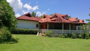 Ein zweistöckiges Haus mit rotem Dach, einer Veranda und einem gepflegten Rasen.