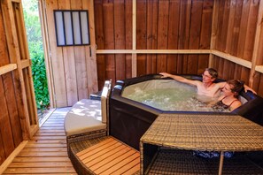 Une cabane en bois avec un jacuzzi et des meubles en osier.