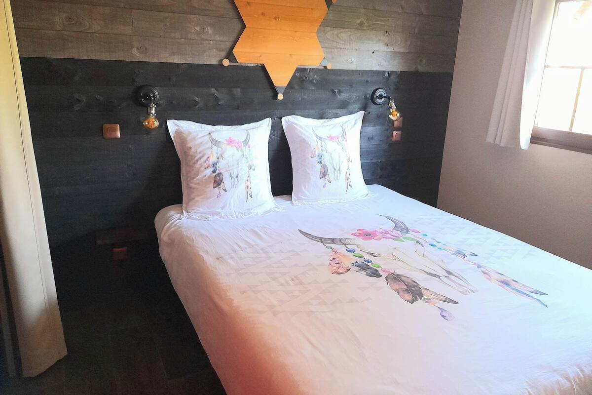 A bed with a geometric-patterned bedspread and two decorative pillows.