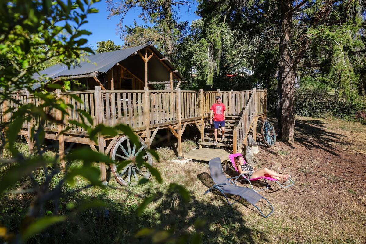 A rustic wooden cabin with a porch, surrounded by trees.