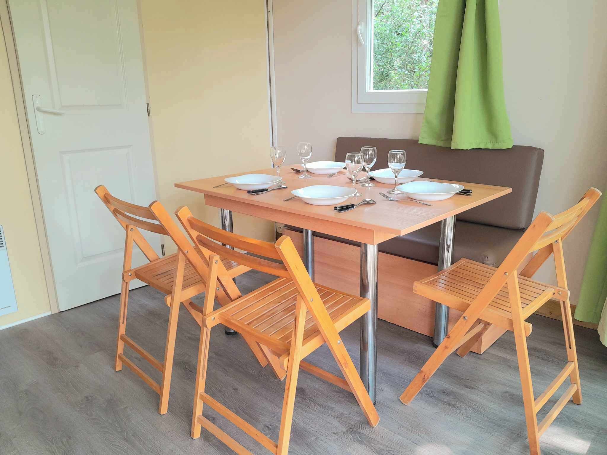 Comedor con mesa de madera dispuesta para cuatro personas, rodeada de sillas de madera.