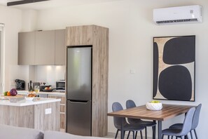 A modern kitchen with a built-in refrigerator, wooden cabinets, and a dining area with a wooden table and chairs. - Protaras Mythical Seas (Paralimni)