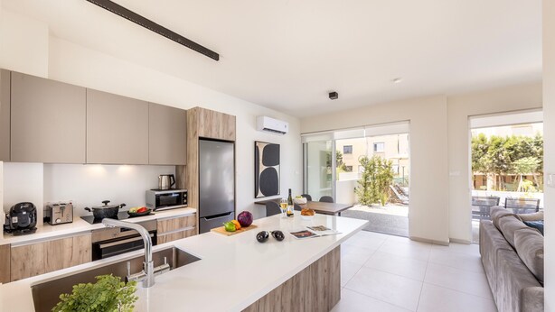 Una cocina moderna con una isla central, electrodomésticos integrados y vistas al área de estar exterior.