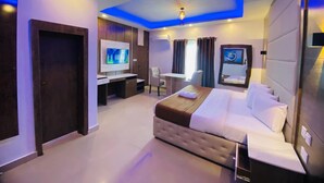 A hotel room with a bed, a desk, a TV, and a seating area. - Presken Oniru (Lagos)