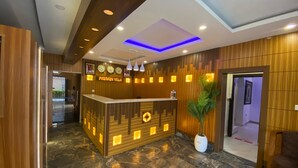 A reception area with a wooden reception desk, a clock, and a potted plant. - Presken Oniru (Lagos)
